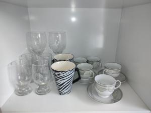 a shelf with wine glasses and cups and plates at 102 Apartamento em Aracruz ES in Aracruz