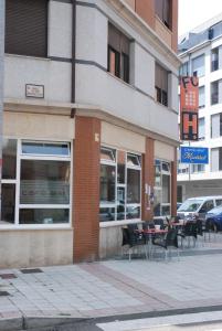 a store with tables and chairs on a city street at Apartahotel FC Catedral in León