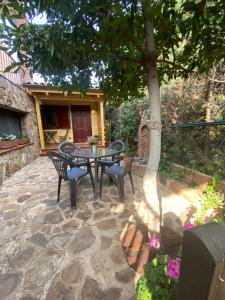 eine Terrasse mit einem Tisch und Stühlen unter einem Baum in der Unterkunft Villa Marín Toledo in Las Nieves