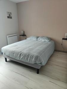 een bed in een witte slaapkamer met een houten vloer bij Gîte de La Gasserotte in Nohant-Vic