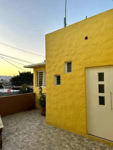 un edificio amarillo con una puerta blanca en el garaje en Departamento completo, cómodo y cerca del aeropuerto en San Agustin de las Juntas