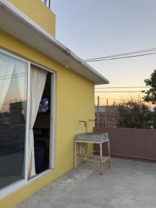 a table sitting on the side of a yellow house at Departamento completo, cómodo y cerca del aeropuerto in San Agustin de las Juntas