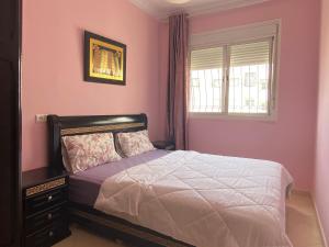 een slaapkamer met roze muren, een bed en een raam bij Échappez à la ville , Appartement près de la nature, entre forêt et plage juste pour les familles in Skhirat