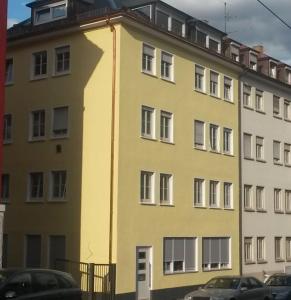 um edifício amarelo com carros estacionados em frente em FeWo - Zur Alten Wäscherei - Zentrumsnah - Garage inklusiv em Estugarda