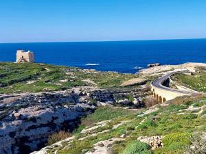 a road on a hill next to the ocean at MJ Farmhouse B&B in Xagħra