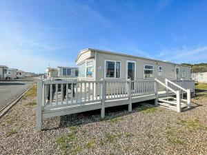 a mobile home with a porch and a fence at Spacious Caravan For Hire With Decking By The Beach In Suffolk Ref 40094nd in Lowestoft