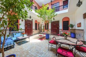 un patio con mesas, sillas y árboles en Riad Todra, en Marrakech