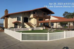 a house with a white fence in front of it at Amazing Lakefront Home with a Private Beach in Lake Elsinore