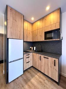 a kitchen with wooden cabinets and a white refrigerator at TideHaven in Palanga +4 photos