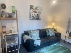 a living room with a black leather couch and a table at Cute+Cozy Guesthouse for 2 +secure offroad parking in Fallings Park