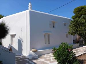a white building with a tree in front of it at Cassaris Mykonos in Drafaki