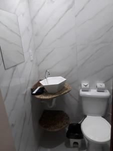 a bathroom with a white toilet and a sink at Pousada Beach House in Cabo Frio
