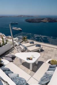 a patio with chairs and a table and the water at Ventus Paradiso Villa in Imerovigli