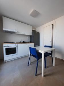 切薩雷奧港的住宿－Kennedy Apartments- Porto Cesareo，厨房配有白色的桌子和2把蓝色的椅子