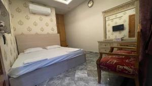een slaapkamer met een bed, een dressoir en een spiegel bij Midways Guest House and Hotels in Islamabad