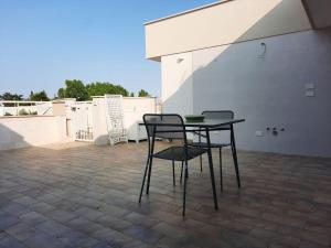 een tafel en 2 stoelen op een patio bij Kennedy Apartments- Porto Cesareo in Porto Cesareo