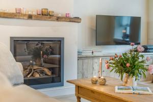 a living room with a fireplace and a table with flowers at VAKANTIEWONING HUYZE ANNE MARIA in Damme