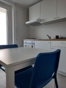 切薩雷奧港的住宿－Kennedy Apartments- Porto Cesareo，厨房配有白色的桌子和蓝色的椅子