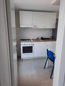 una cocina con armarios blancos y una silla azul en Kennedy Apartments- Porto Cesareo, en Porto Cesareo