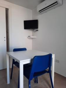 een wit bureau met twee blauwe stoelen en een televisie bij Kennedy Apartments- Porto Cesareo in Porto Cesareo