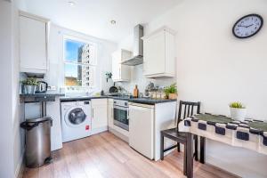 una cucina con armadi bianchi, lavandino e tavolo di Cosy flat in Central LDN Payment to the HOST a Londra