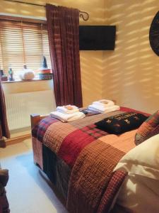 a bedroom with a bed with towels on it at Bumbleberry Cottage in Gresford