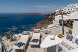 una mesa y sillas en un balcón con vistas al océano en Ventus Paradiso Villa en Imerovigli