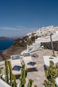 un patio con sillas blancas y vistas al océano en Ventus Paradiso Villa en Imerovigli