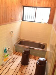 eine Badewanne in einem Badezimmer mit zwei Mülleimern in der Unterkunft Minshuku nicoichi in Yakushima + 33 Fotos