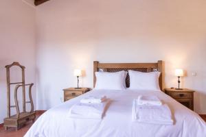 um quarto com uma cama branca com duas toalhas em Horta dos Caracóis em Borba