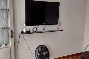 uma televisão de ecrã plano numa parede com uma ventoinha em Grandes Grupos Casa 1 em São Paulo