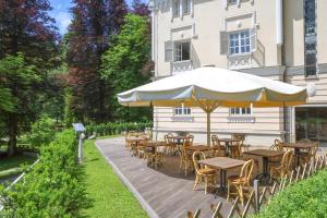 un patio con tavoli, sedie e ombrellone di Depandance Vila Higiea - Terme Dobrna a Dobrna