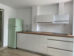 una cucina con armadi bianchi e frigorifero verde di Apartamento turístico Ático La Piterilla a Huelva
