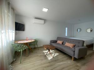 Apartamento turístico Ático La Piterilla في هويلفا: غرفة معيشة مع أريكة وطاولة وسرير
