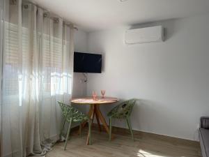 un tavolo con due sedie e una televisione in una stanza di Apartamento turístico Ático La Piterilla a Huelva