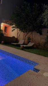 a blue swimming pool in a yard at night at villa saada in Marrakesh