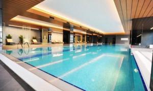 a large swimming pool with blue water in a building at Luxury 1+1 apt in Sinpaş Queen Bomonti in Istanbul