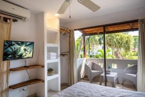 a bedroom with a bed and a tv and a balcony at Hermosa Palms Casa 23B -3BD - Bruno Casalvolone in Jacó