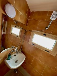 een badkamer met een wastafel, een spiegel en een raam bij Hotel Kappa3 Villas in Vlorë