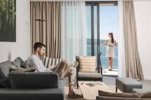 布德瓦Boutique Hotel Shell的坐在客厅长沙发上的男人和女人