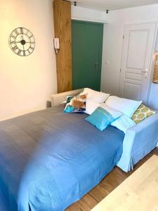 a blue bed with pillows and a clock on the wall at Apartment with mountain views in town centre in La Roche-sur-Foron