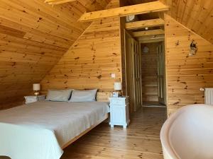 1 dormitorio con cama y bañera en el techo de madera en CSENDÜLŐ VENDÉGHÁZ, en Noszvaj