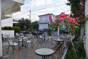 eine Terrasse mit Tischen, Stühlen und Blumen in der Unterkunft Anaxos Bay Rooms & Apartments in Anaxos