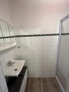 een witte badkamer met een wastafel en een douche bij Ferienhaus Flensburg Sandberg in Flensburg