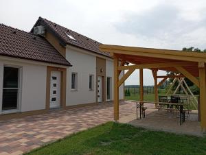 a pavilion with a picnic table on a patio at Vadgalamb Apartmanház in Lipót