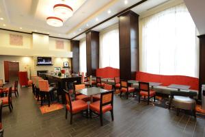 a dining room with tables and chairs and windows at Hampton Inn & Suites Albany at Albany Mall in Albany