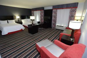a hotel room with two beds and a red couch at Hampton Inn & Suites Albany at Albany Mall in Albany +32 photos