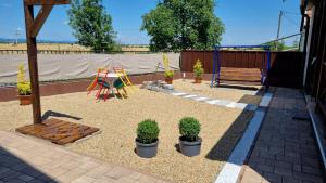 a backyard with a playground and a bench and plants at HT Apartman in Mezőkövesd