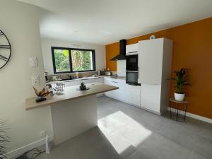 a large kitchen with white cabinets and a window at Maison spacieuse, centre sarzeau in Sarzeau