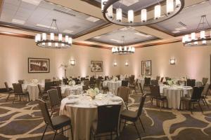 una sala de banquetes con mesas, sillas y lámparas de araña en Embassy Suites Saratoga Springs en Saratoga Springs